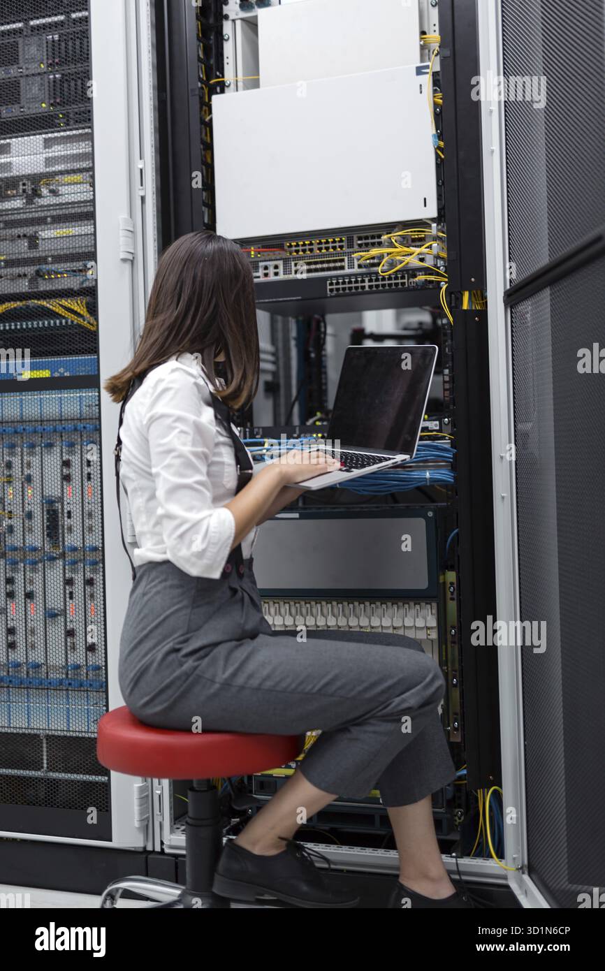 Technician apecialist woman using laptop while analyzing server in server room Stock Photo