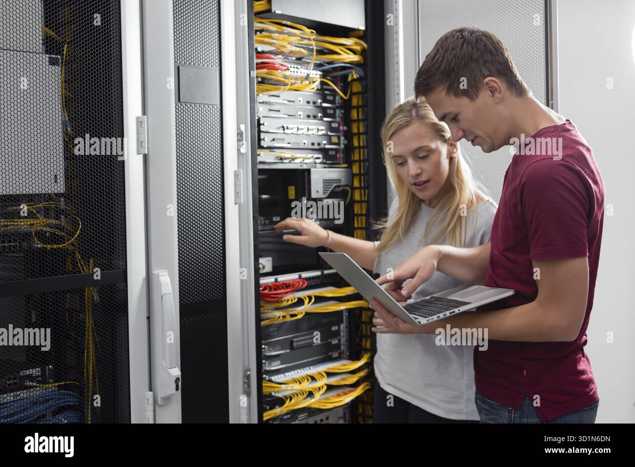 Team of technicians working together on servers at the data centre Stock Photo