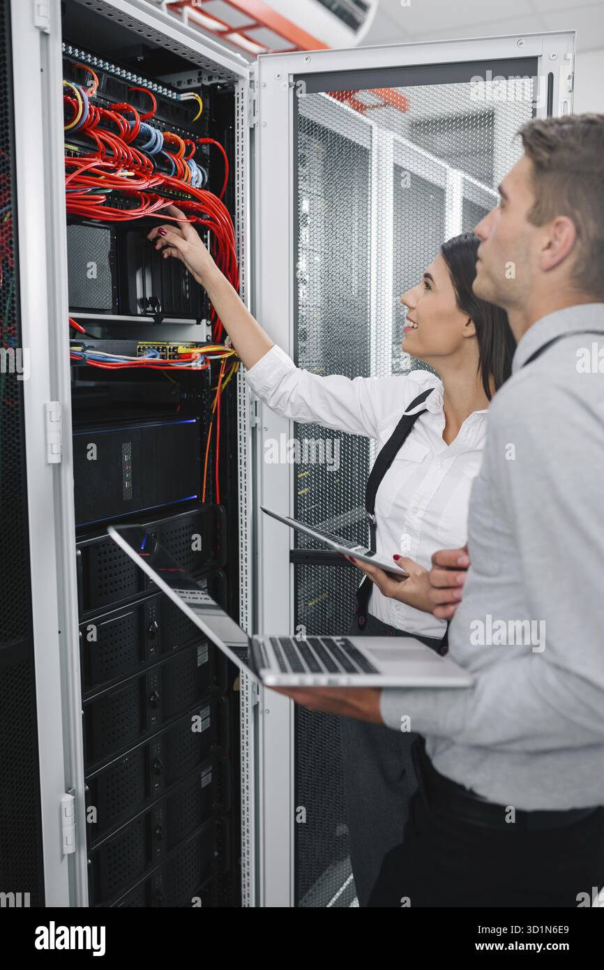 Team of technicians working together on servers at the data centre Stock Photo