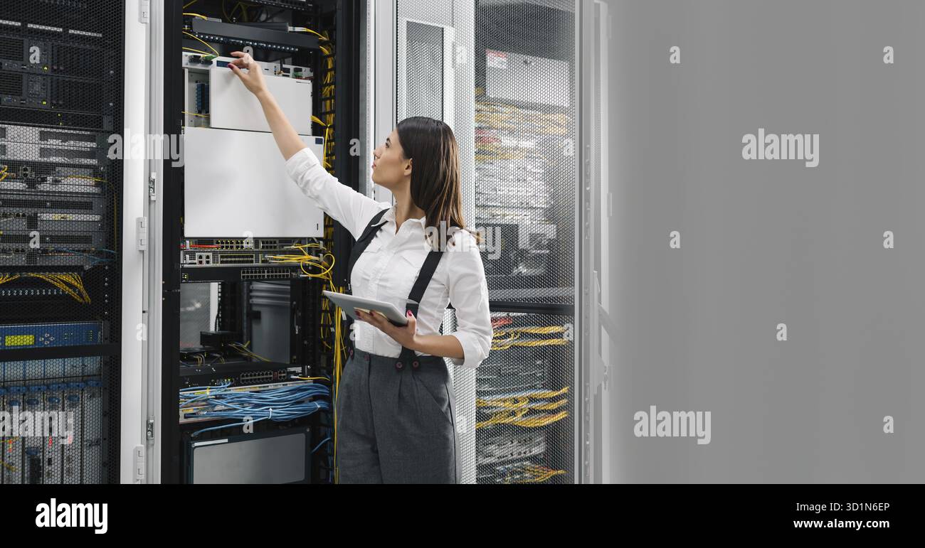 Technician using tablet pc while analysing server in large data center Stock Photo