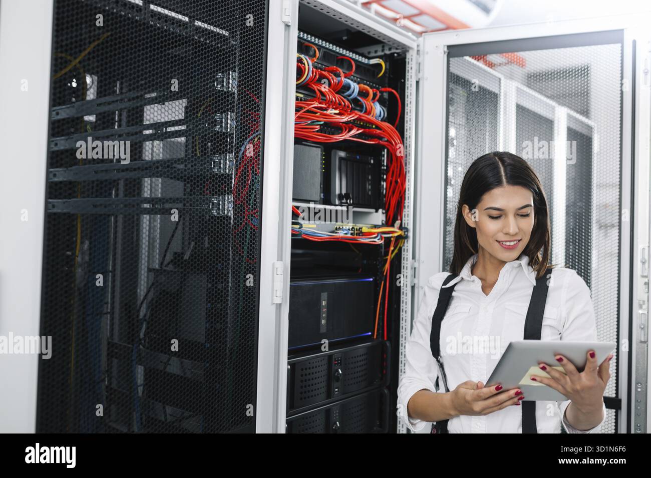Technician using tablet pc while analysing server in large data center Stock Photo