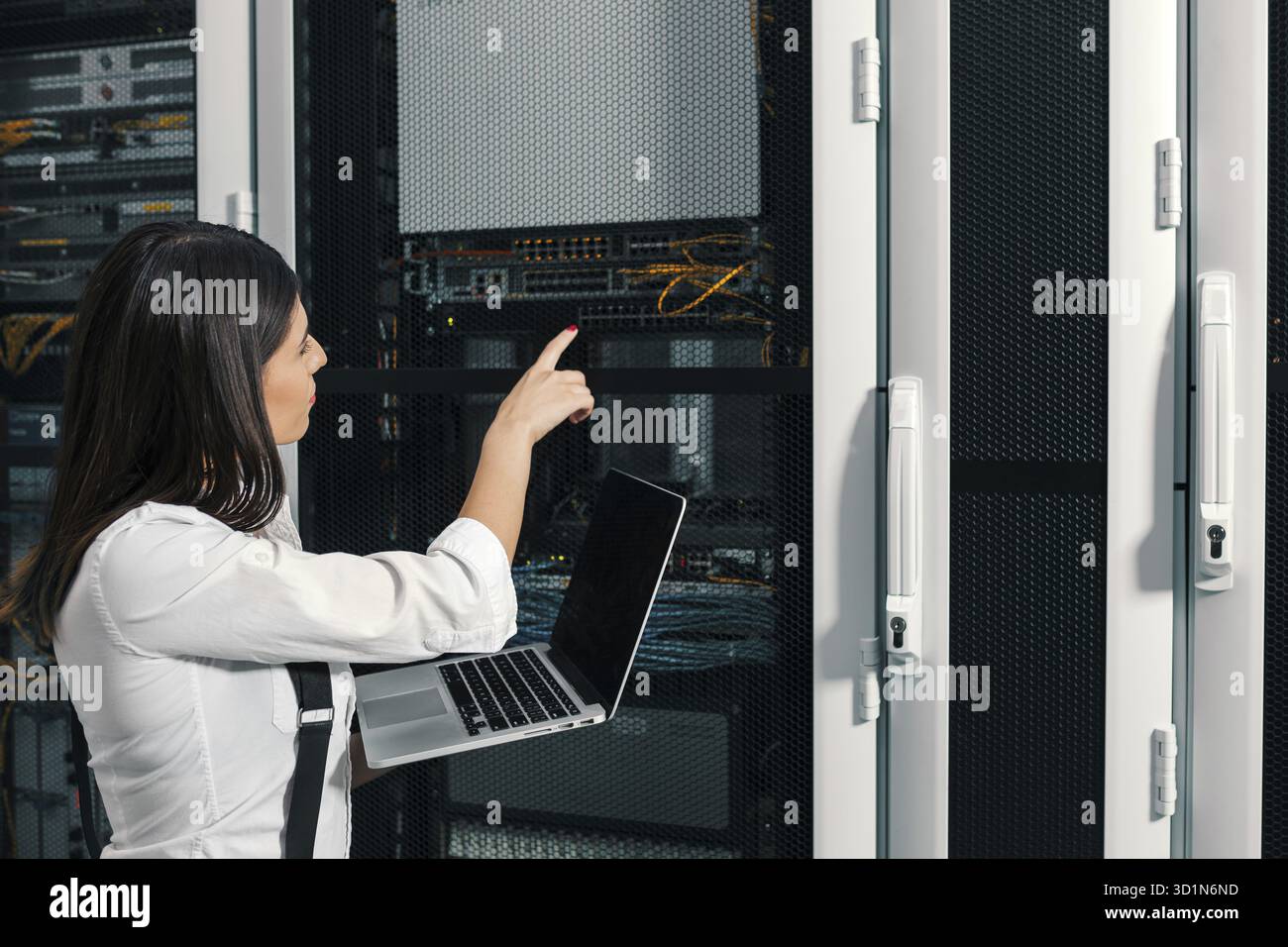 Technician apecialist woman using laptop while analyzing server in server room Stock Photo