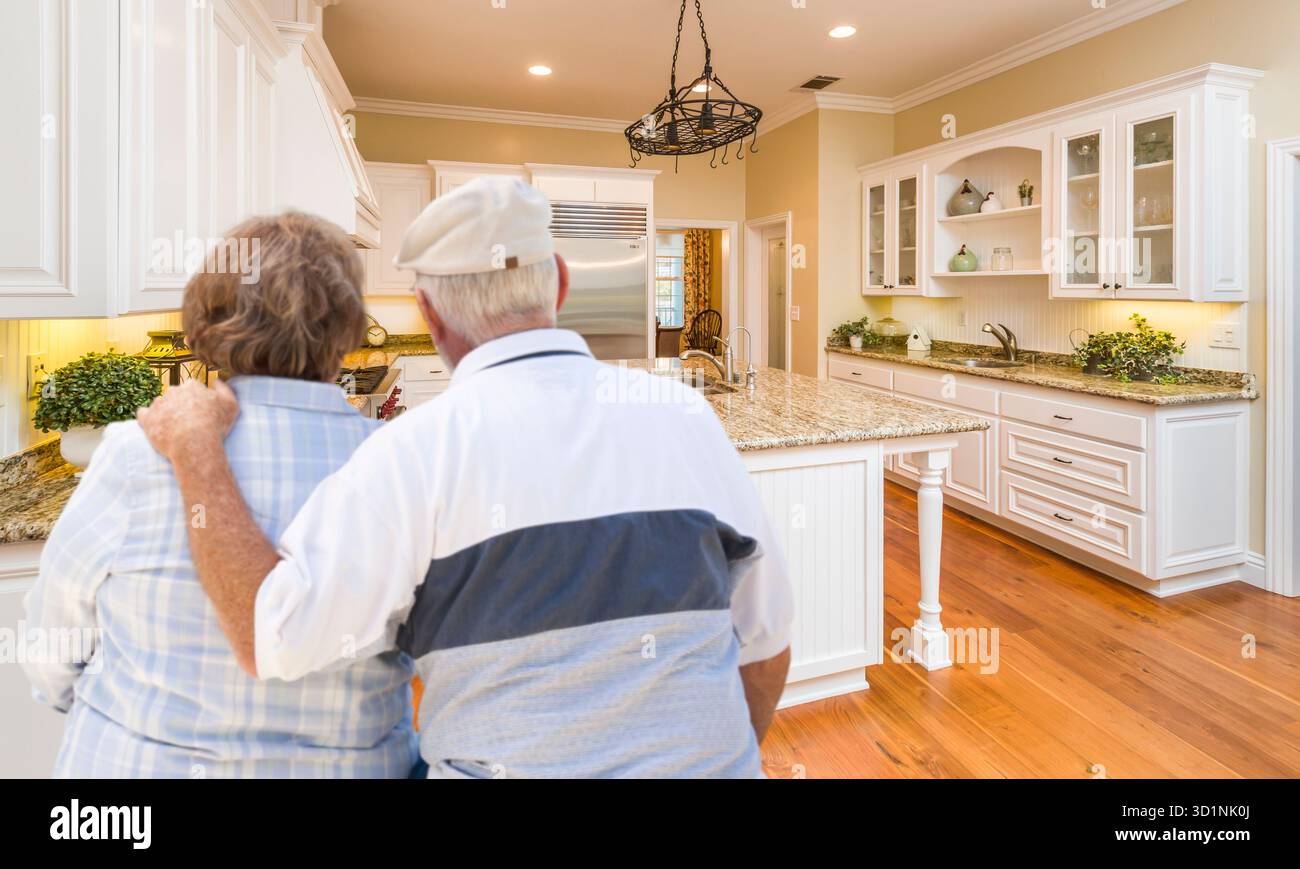 Senior Couple Looking Over Beautiful Custom Kitchen Stock Photo