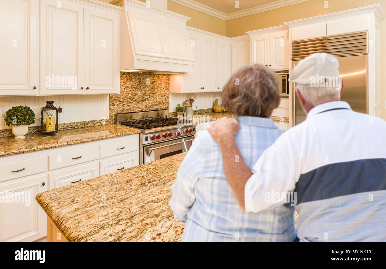 Senior Couple Looking Over Beautiful Custom Kitchen Stock Photo