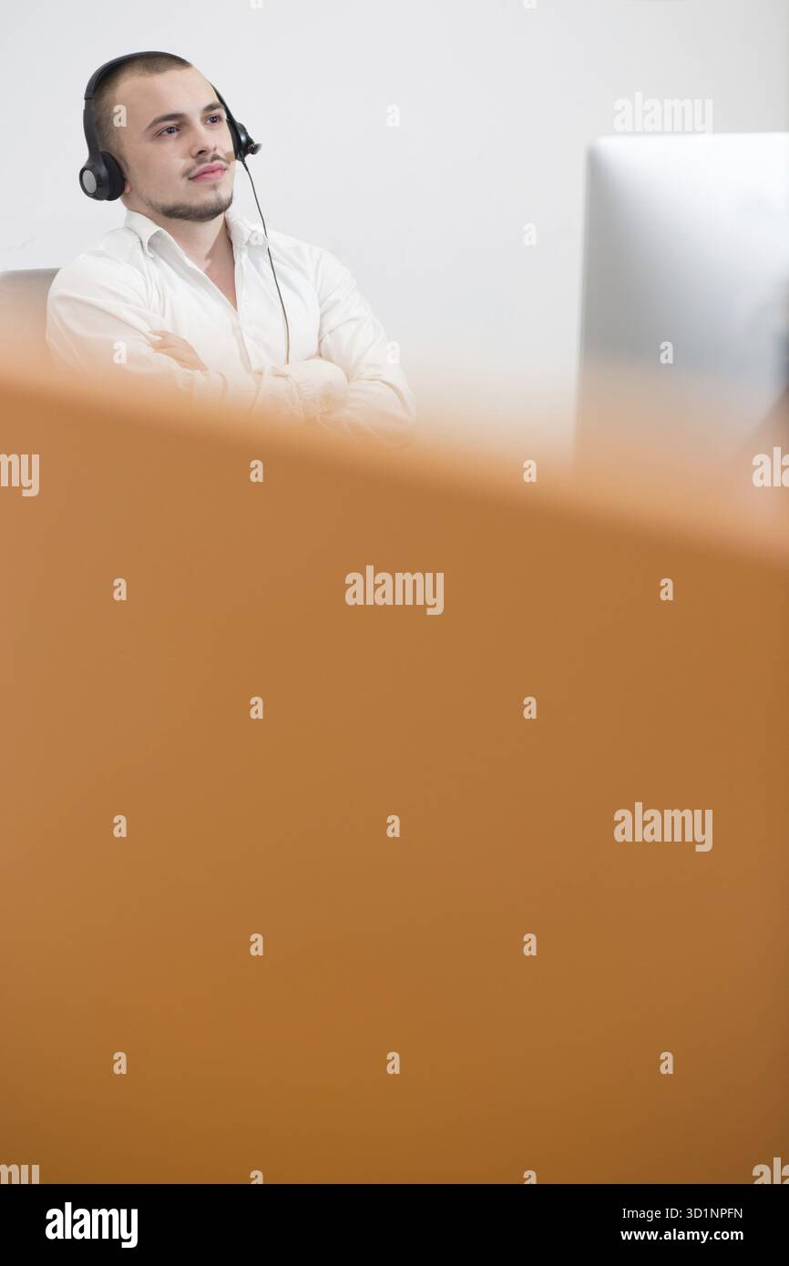 Smiling casual young man with headset using computer in a bright office Stock Photo