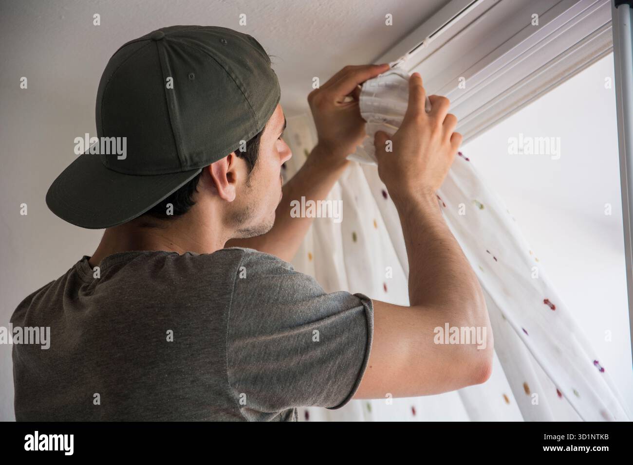Young man installing curtains over window Stock Photo