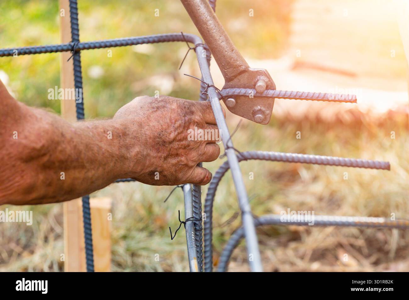 Worker Using Tools To Bend Steel Rebar At Construction Site Stock Photo