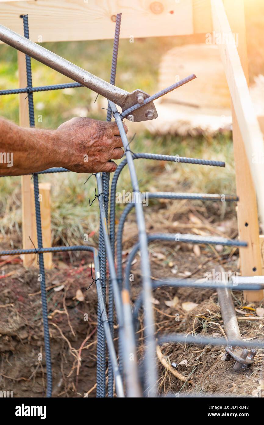 Worker Using Tools To Bend Steel Rebar At Construction Site Stock Photo
