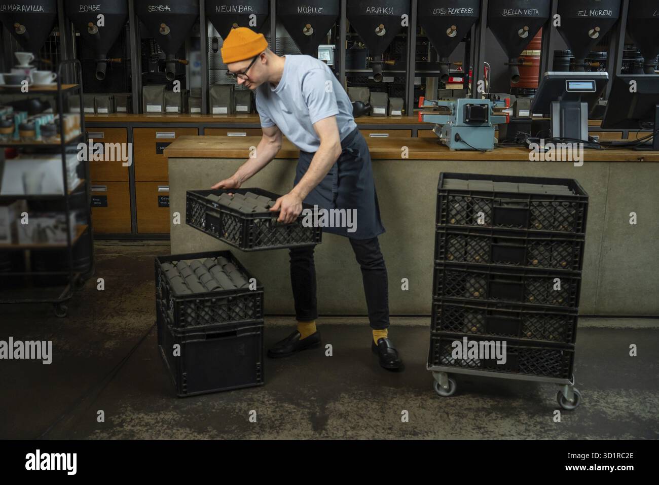 Male worker or business owner uploads packages of coffee on factory or warehouse, barista in coffee shop Stock Photo