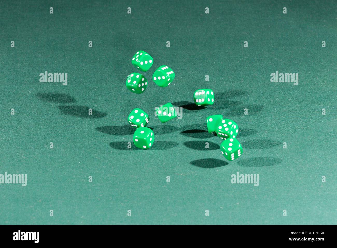 Ten green dices falling on a green table Stock Photo