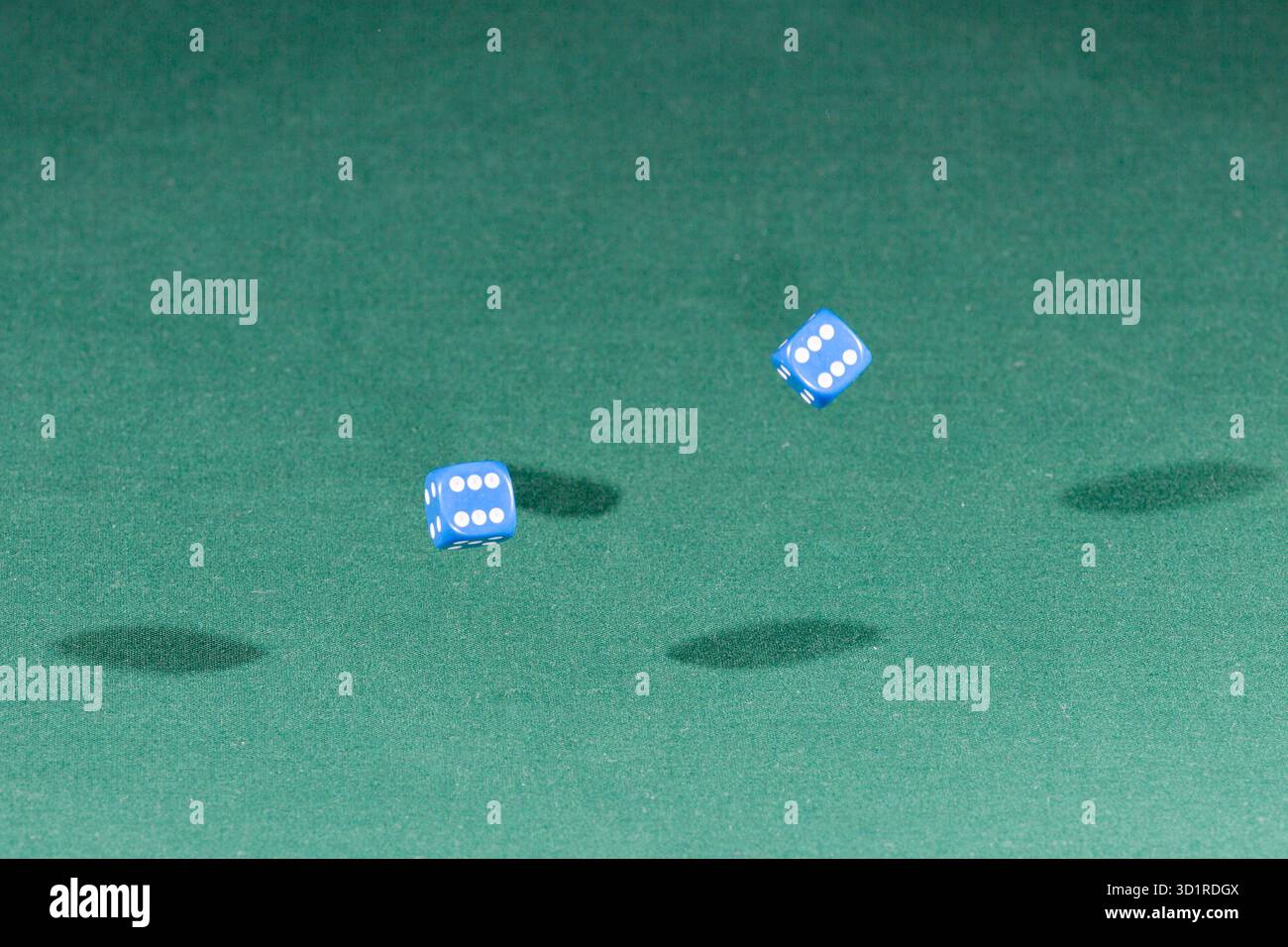 Two blue dices falling on a green table Stock Photo
