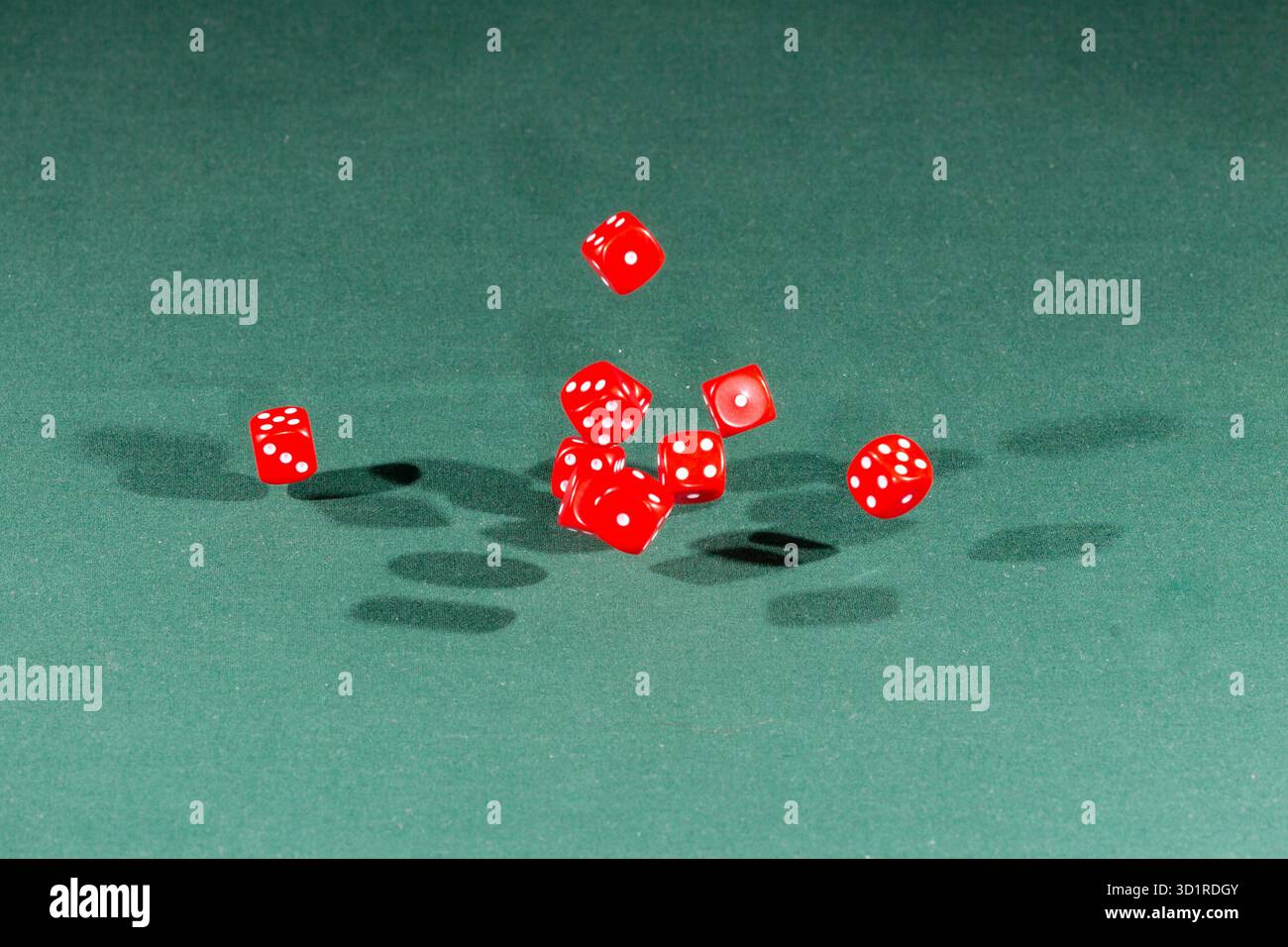 Ten red dices falling on a green table Stock Photo