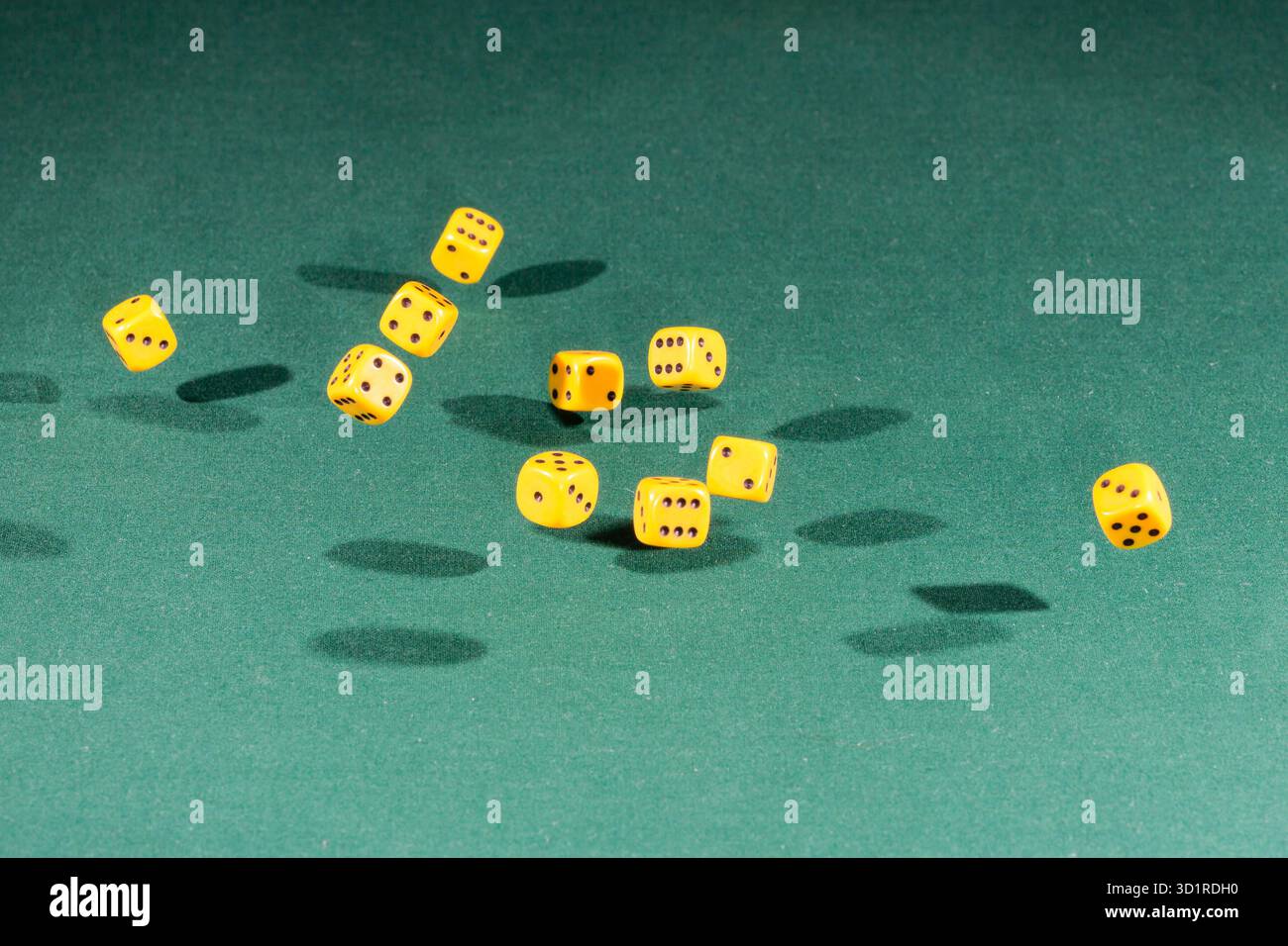 Ten yellow dices falling on a green table Stock Photo