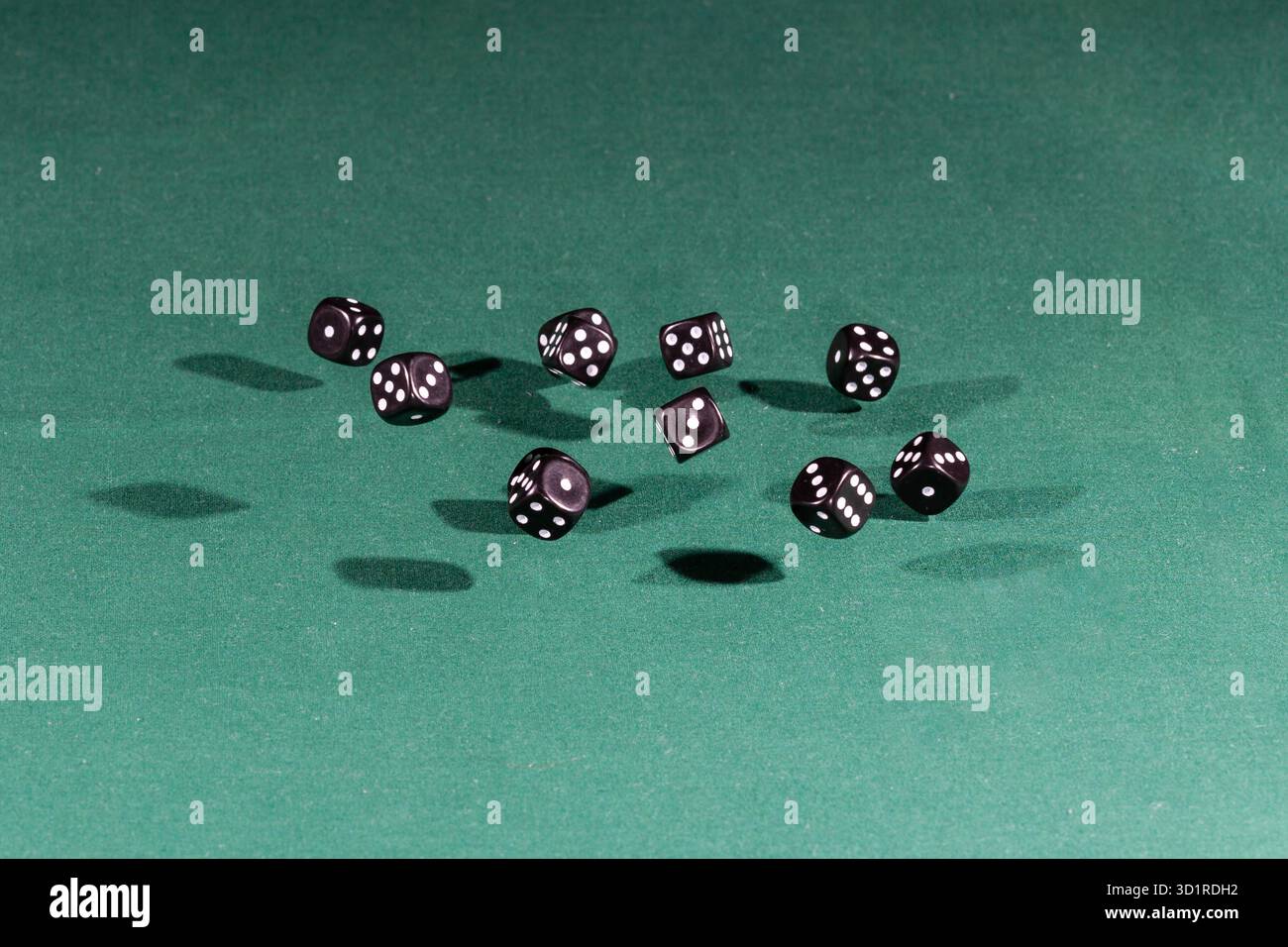 Ten black dices falling on a green table Stock Photo