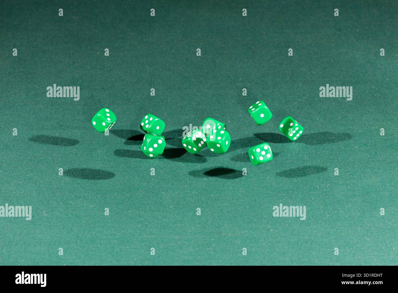 Ten green dices falling on a green table Stock Photo