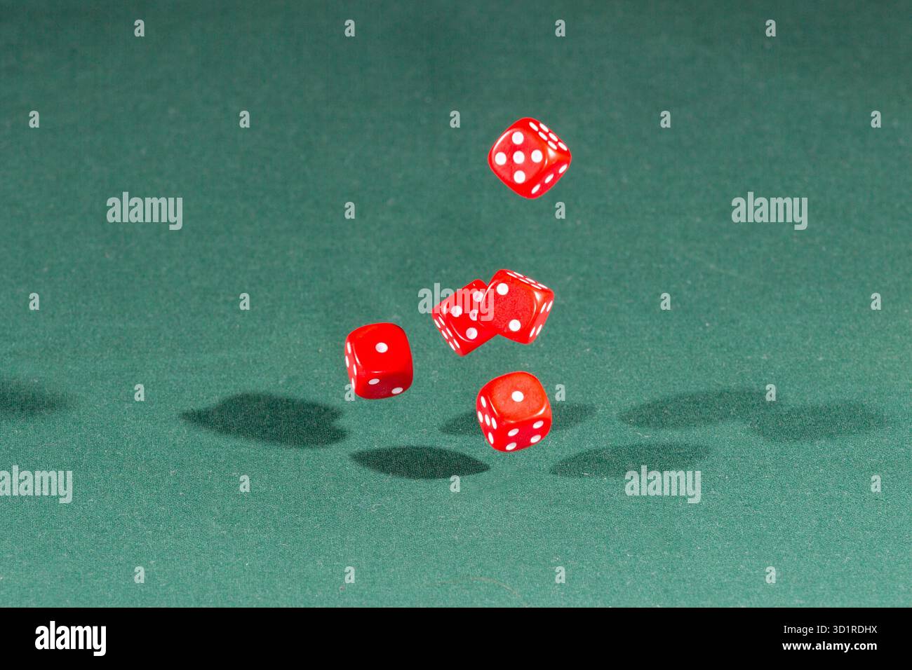 Five red dices falling on a green table Stock Photo