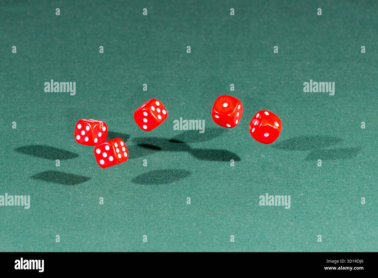 Five red dices falling on a green table Stock Photo