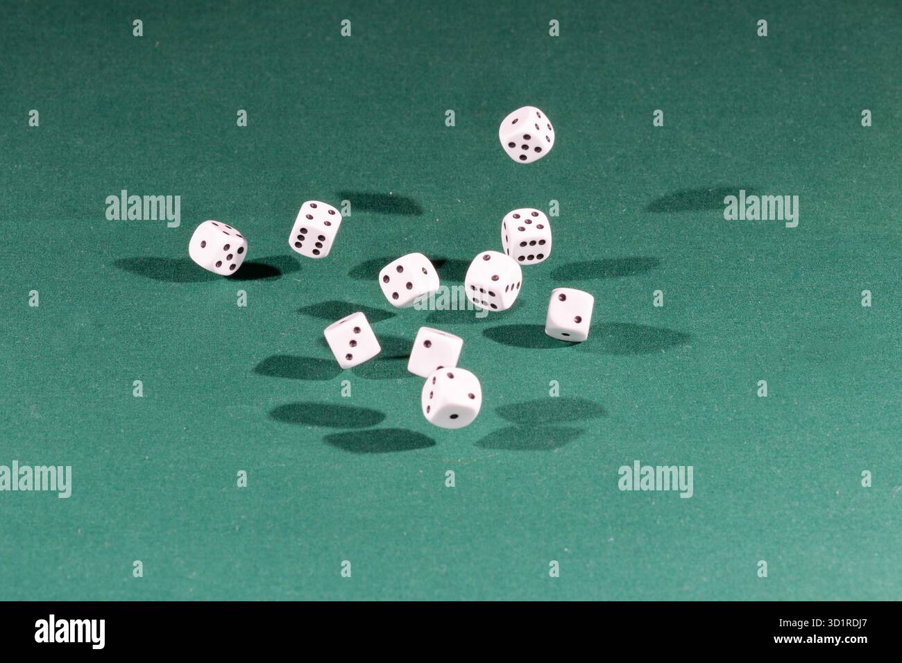 Ten white dices falling on a green table Stock Photo