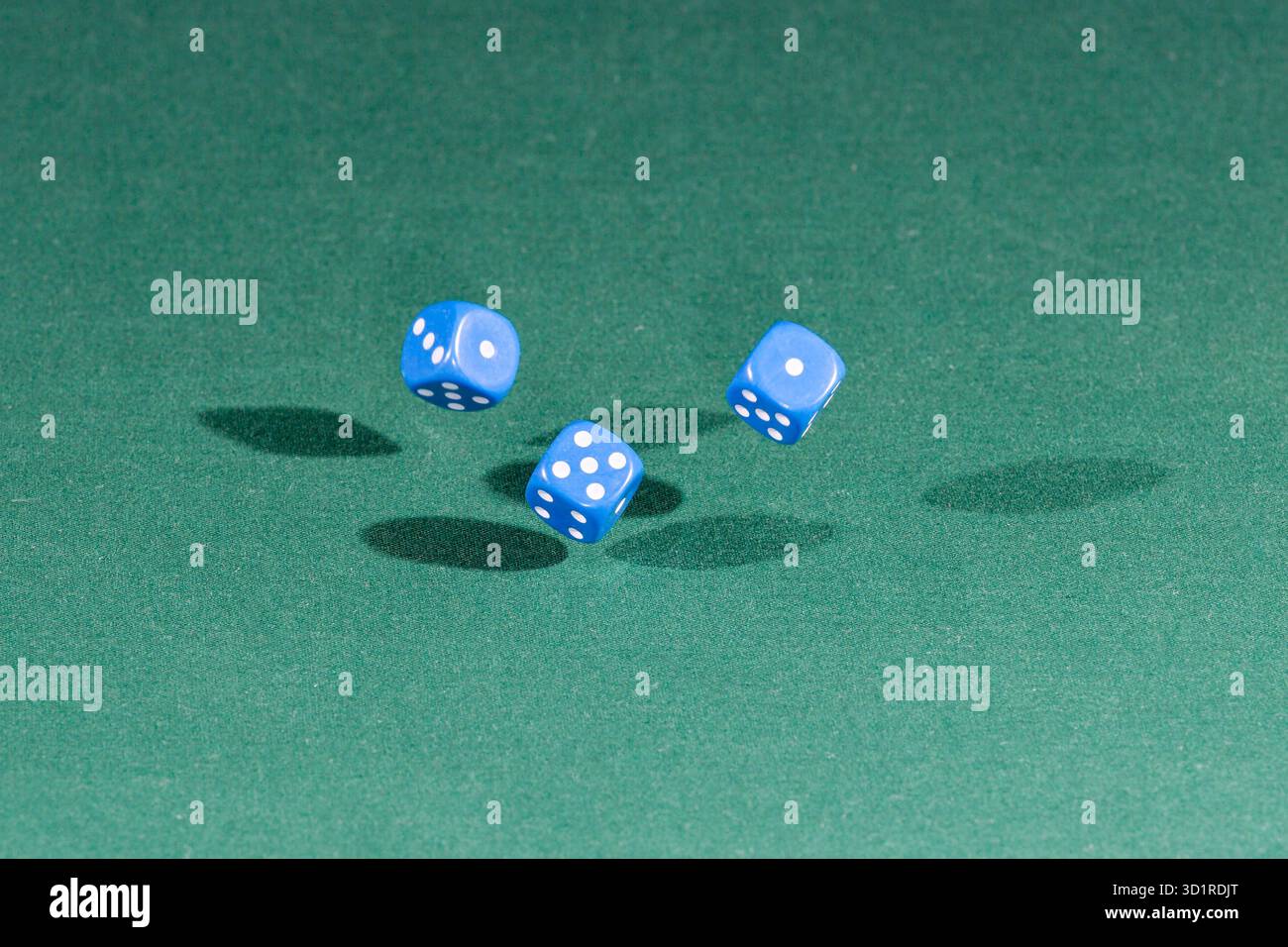 Three red dices falling on a green table Stock Photo