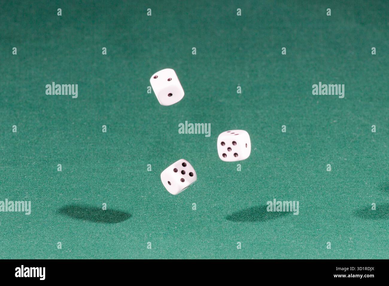 Three white dices falling on a green table Stock Photo