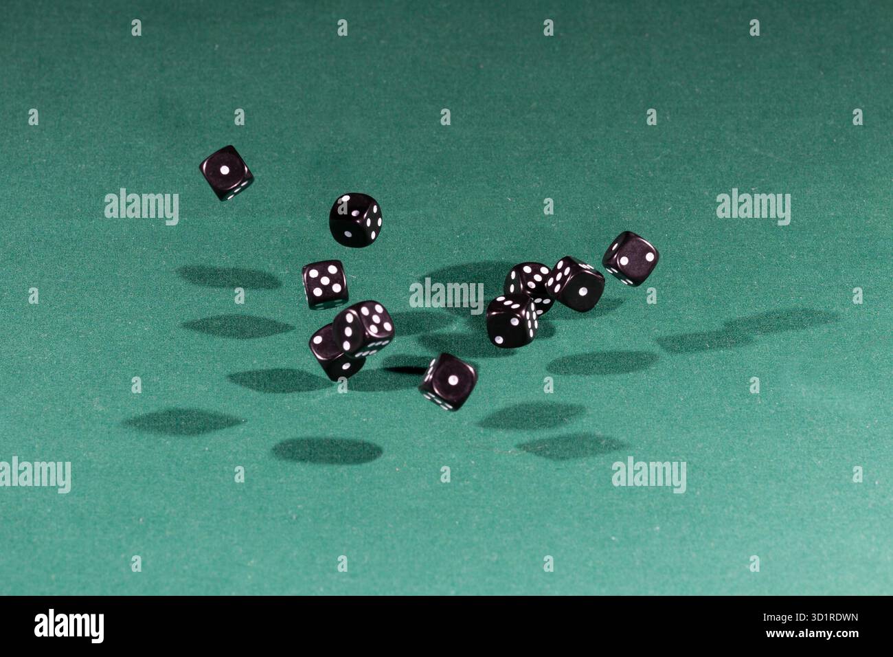 Ten black dices falling on a green table Stock Photo