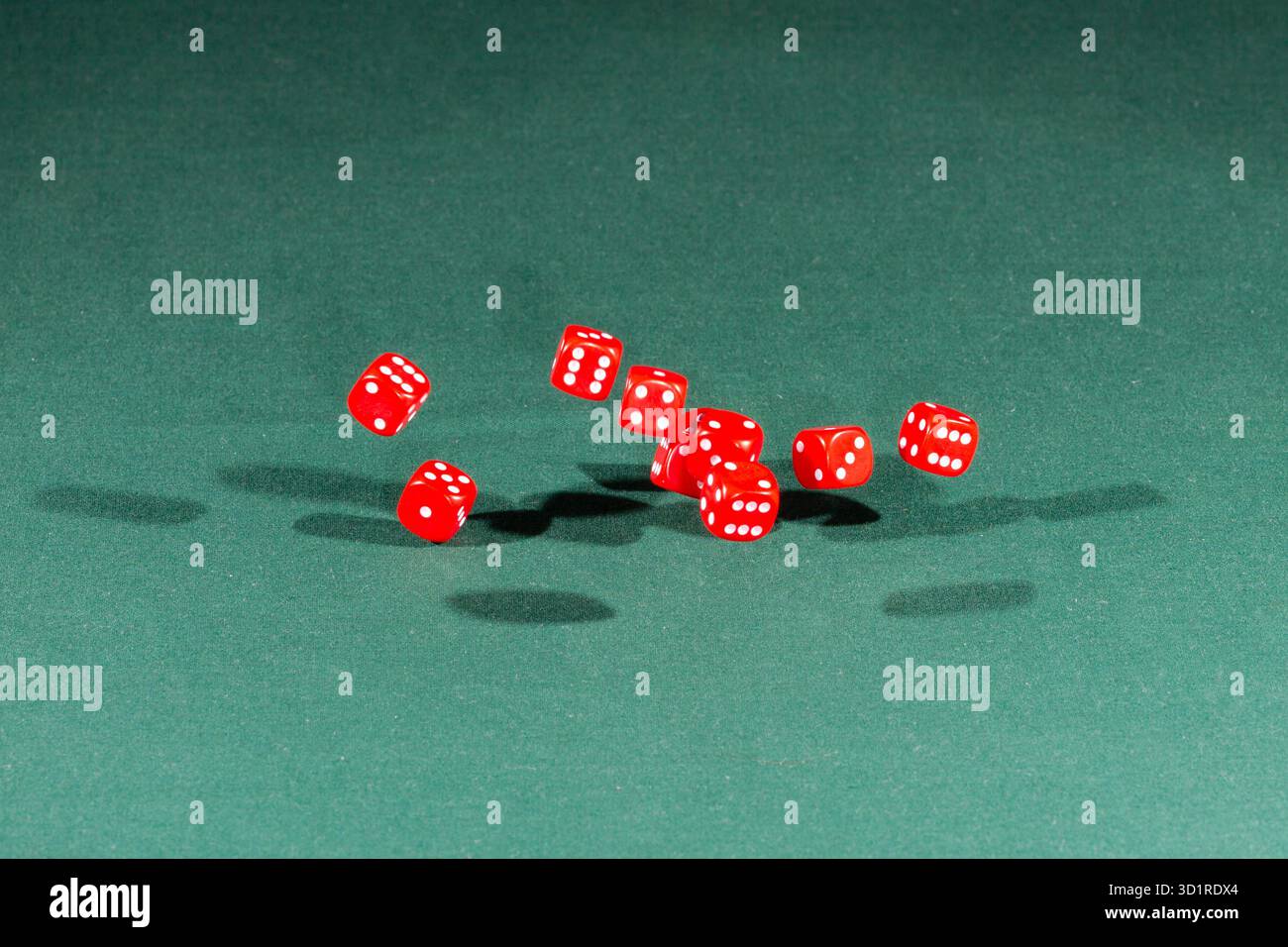 Ten red dices falling on a green table Stock Photo