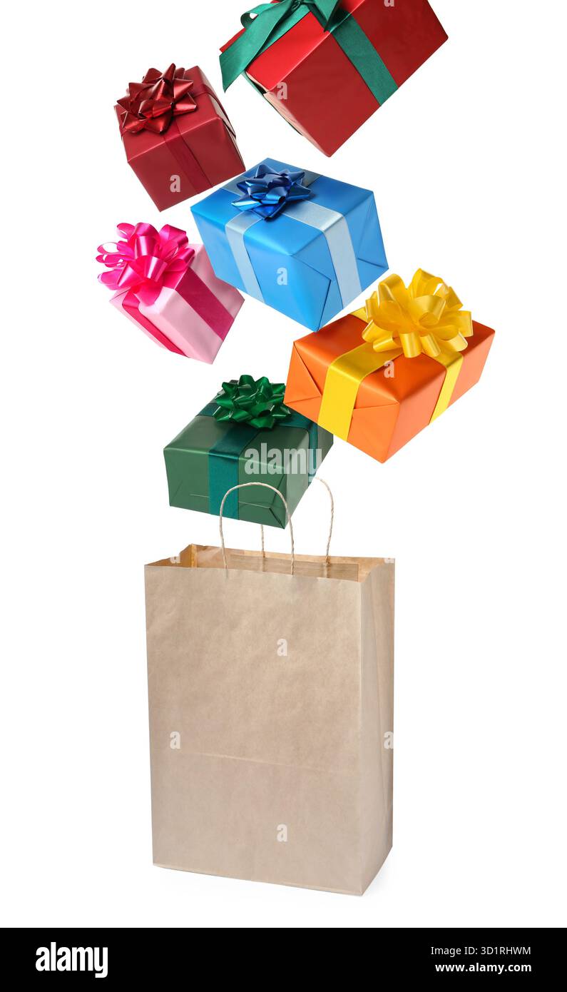 Many gift boxes falling into paper bag on white background Stock Photo