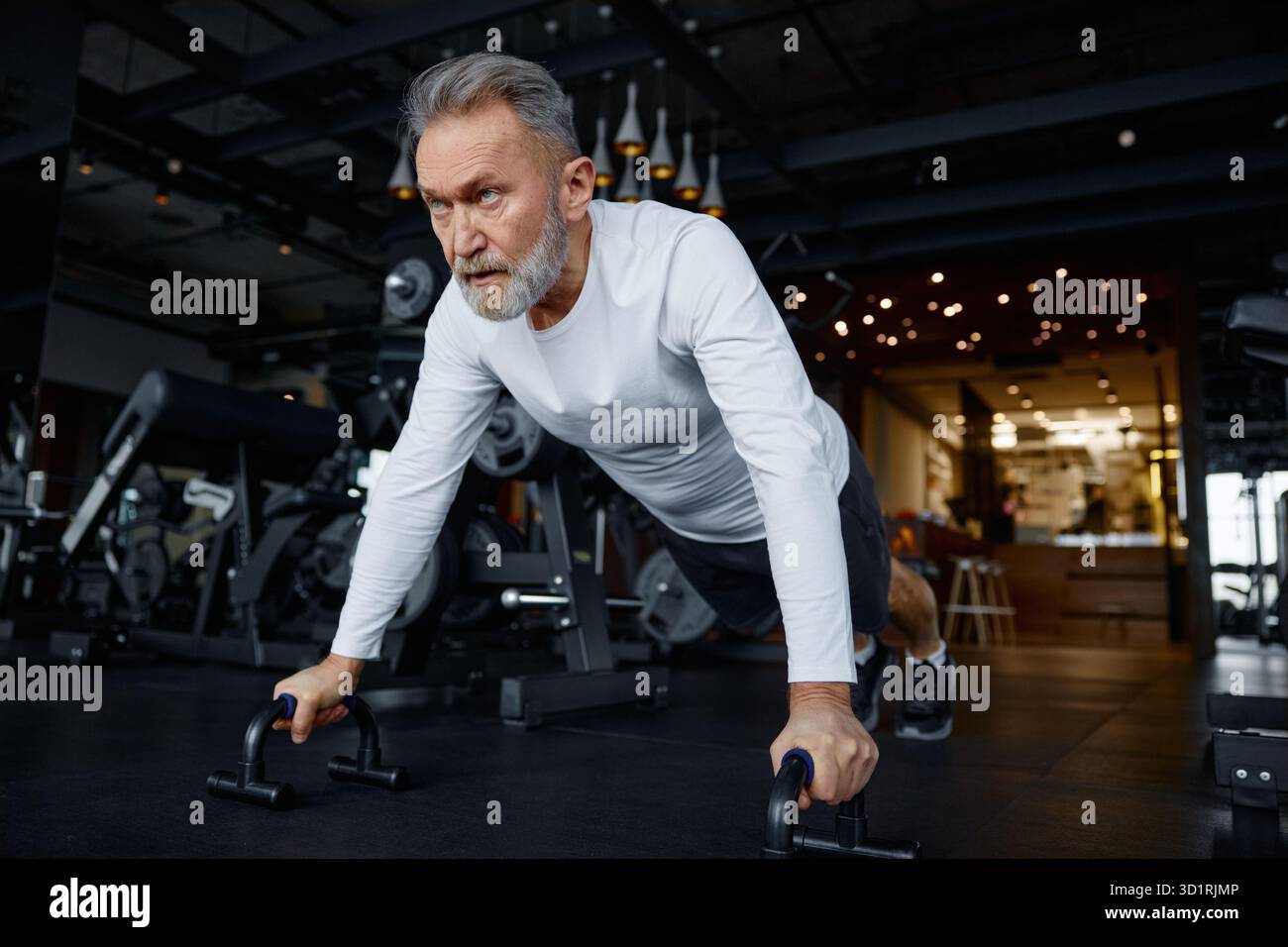 Mature man is doing push-ups in a modern gym Stock Photo