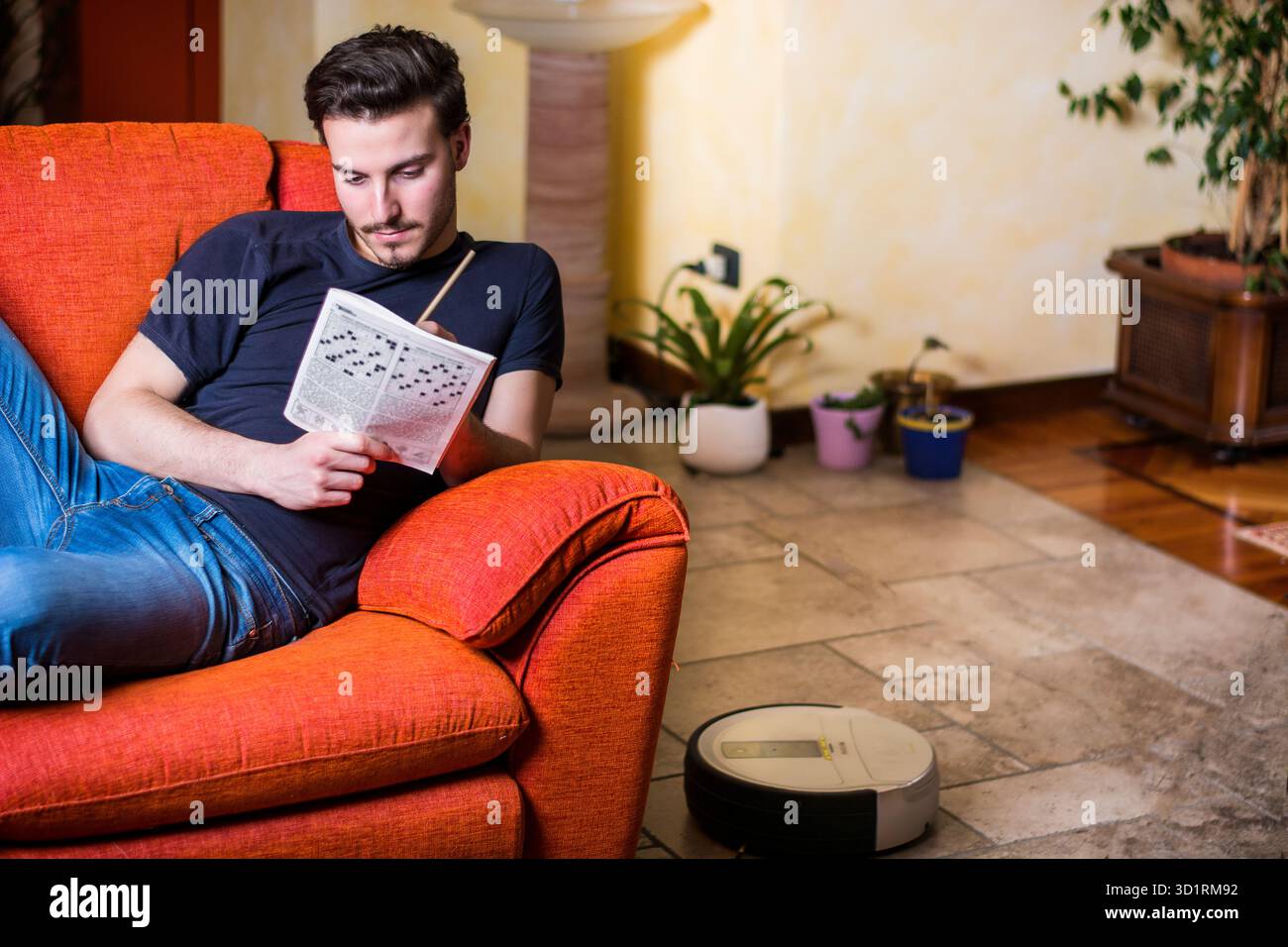 Young man sitting doing a crossword puzzle Stock Photo