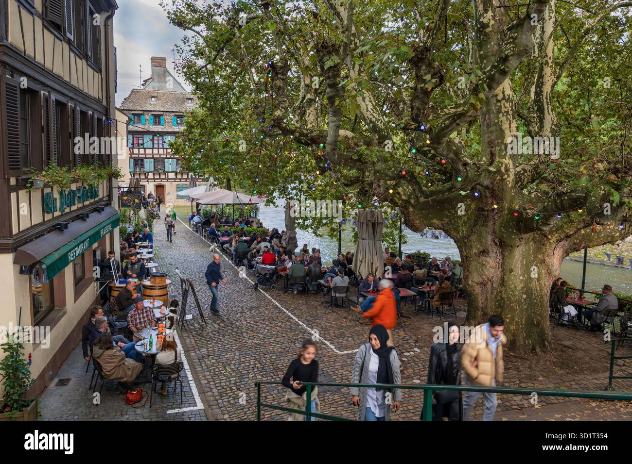 Strasbourg, France - October 5, 2024 - The Petite France quarter, people dining at Au Petit Bois Vert restaurant outdoor tables on Quai de la Bruche ( Stock Photo