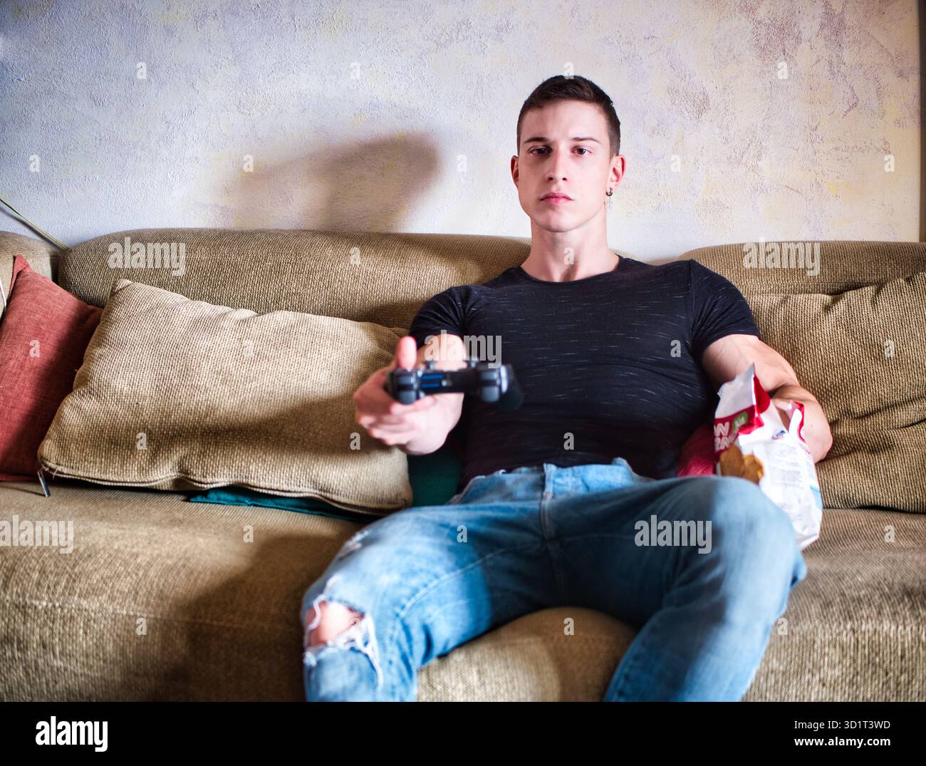 Attractive guy playing videogames with joystick in hand Stock Photo