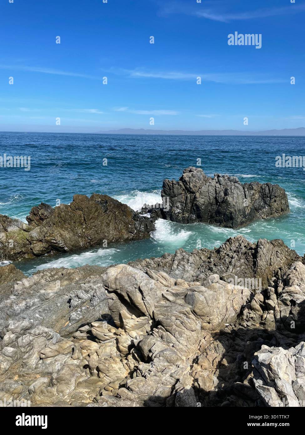 Rocky coastline with ocean waves and clear blue sky, Pacific coast of Mexico - Smartphone Captured Stock Image