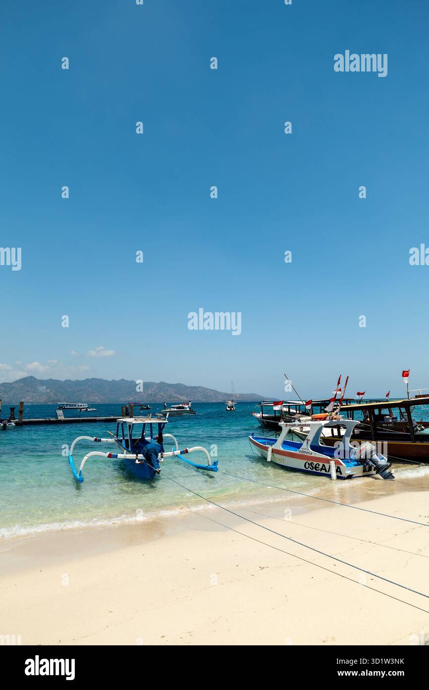 Lombok, Indonesia - 10.02.2023: Tropical sandy beach with turquoise ocean and tourist boats at Gili Islands. Stock Photo