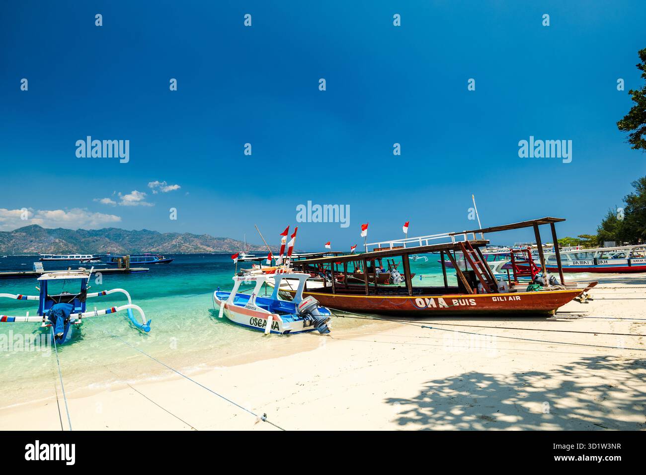 Lombok, Indonesia - 10.02.2023: Tropical sandy beach with turquoise ocean and tourist boats at Gili Islands. Stock Photo