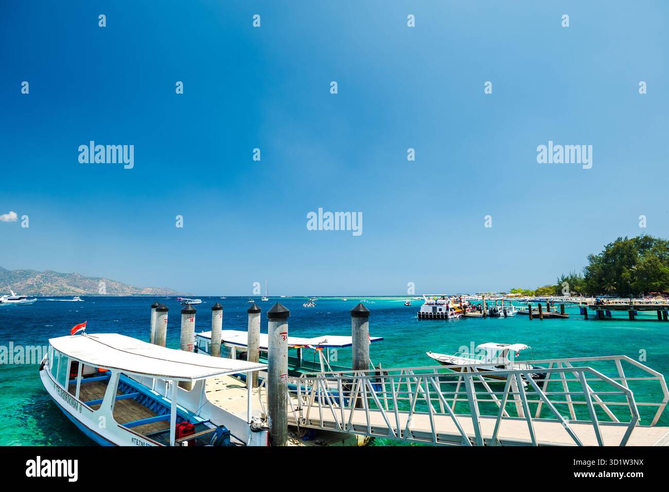 Lombok, Indonesia - 10.02.2023: Tropical sandy beach with turquoise ocean and tourist boats at Gili Islands. Stock Photo