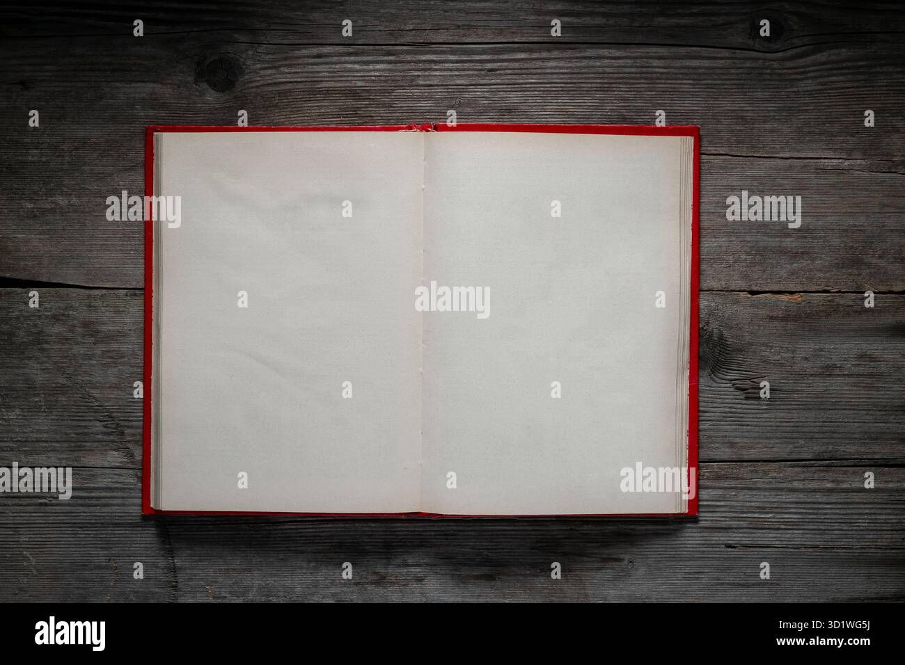 Open blank book on a rustic dark wooden background. Red cover, empty pages. Stock Photo