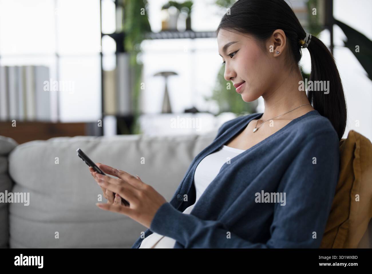 Asian Woman using smartphone mobile addict spending time checking social media on sofa at home cell telephone technology socia Stock Photo