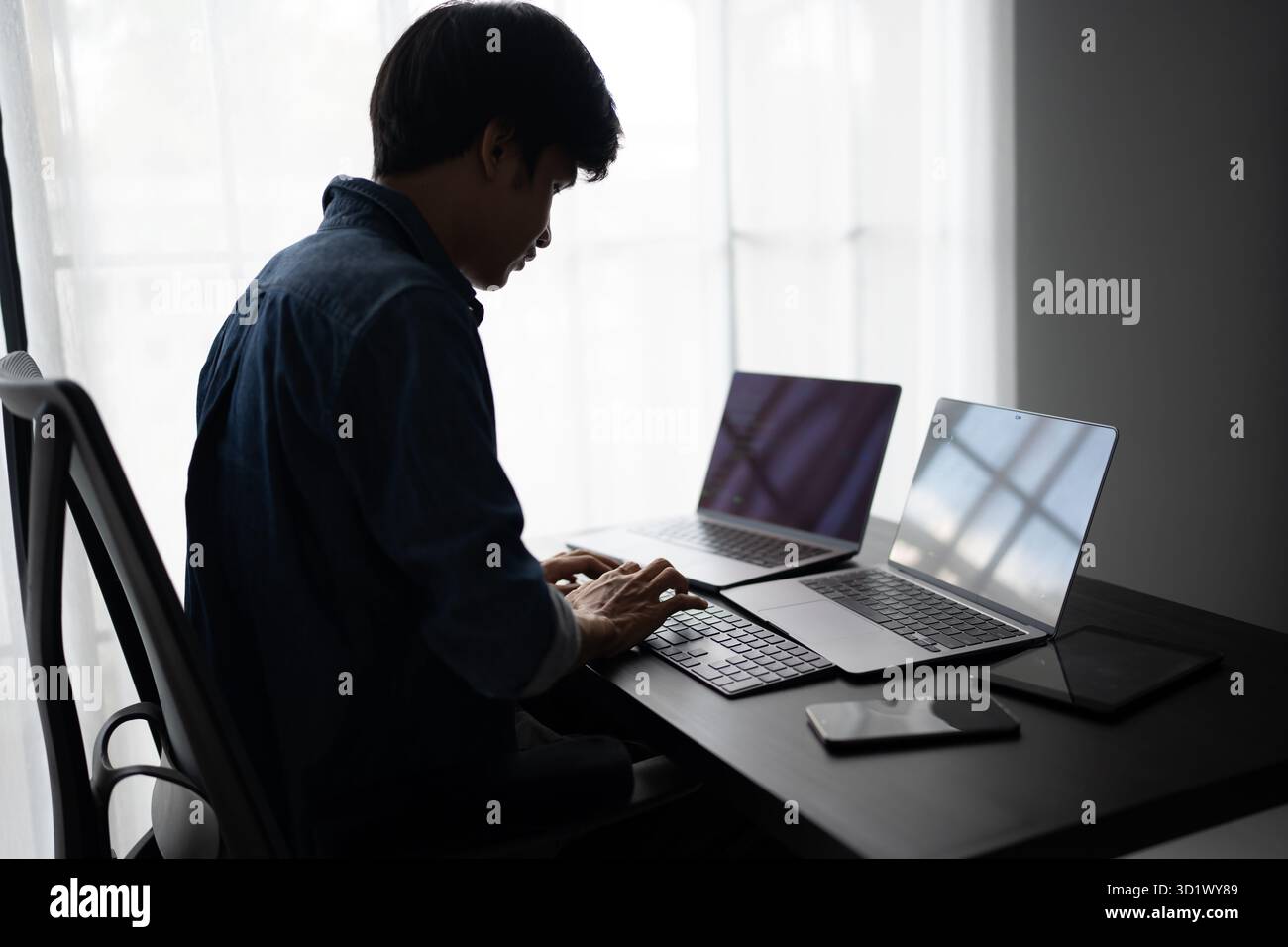 Asian man software engineer Working on Computer at office desk for writing program code IT Software Engineer finding errors tech Stock Photo