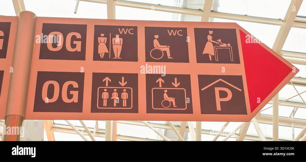 Belin, Germany - May 19, 2025: Directional sign displays icons for restrooms, elevators, and parking areas. - Smartphone Captured Stock Image