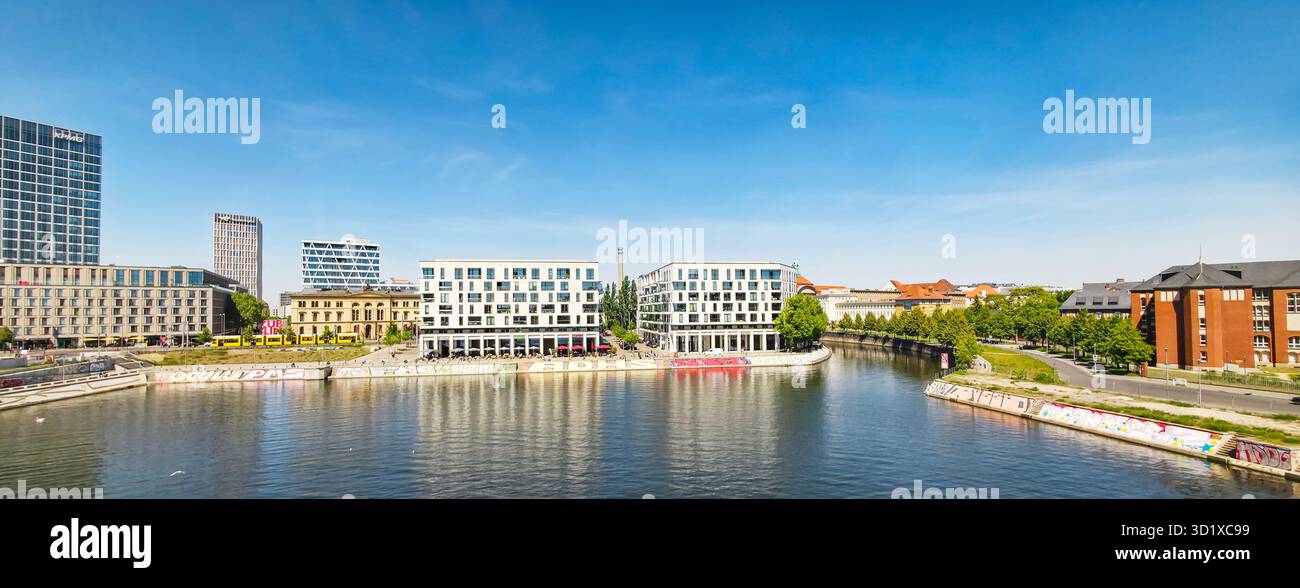 Berlin, Germany - May 13, 2025: Modern architecture along the waterfront with clear blue sky and reflections on the water surface. - Smartphone Captured Stock Image