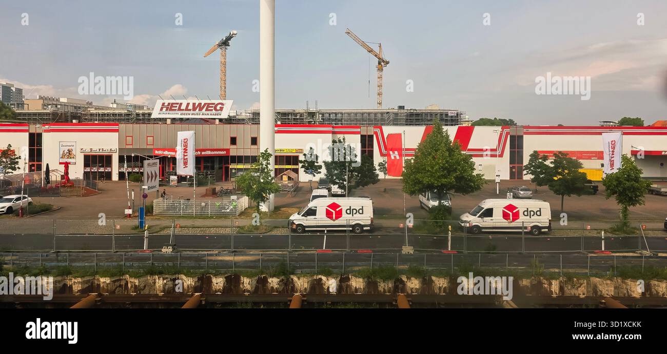 Berlin, Germany - June 02, 2025: Hellweg hardware store features delivery vans and construction site in background. - Smartphone Captured Stock Image