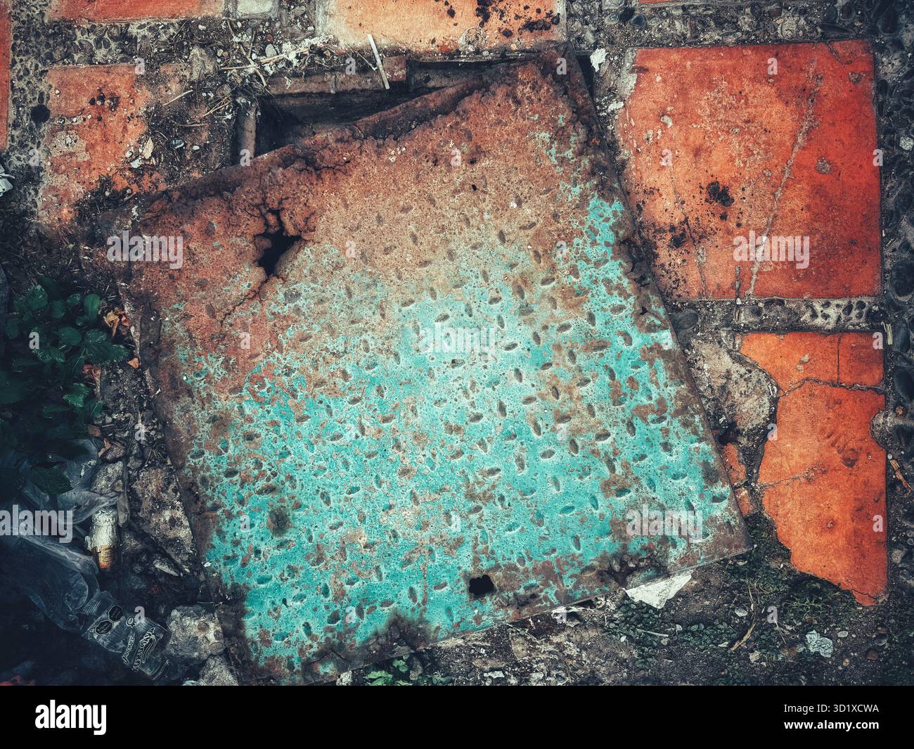 Old rusted and weathered metal plate with peeling turquoise paint lying on broken red tiles and crumbling ground - Smartphone Captured Stock Image