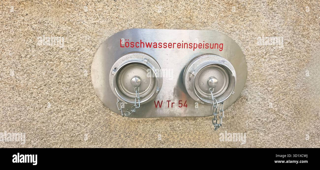 Berlin, Germany - June 02, 2025: Fire water supply connection features two outlets mounted on textured wall surface. - Smartphone Captured Stock Image