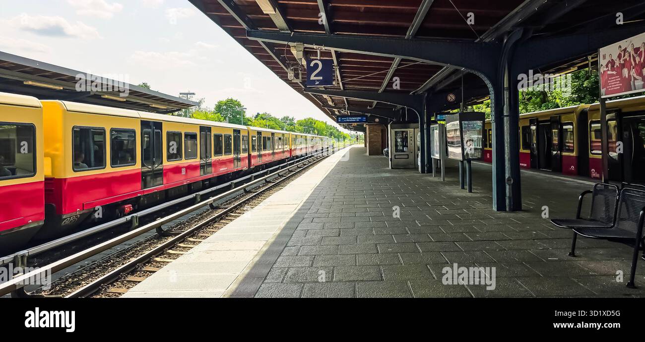 Berlin, Germany - June 11, 2025: Train station platform features yellow and red commuter trains along the tracks. - Smartphone Captured Stock Image
