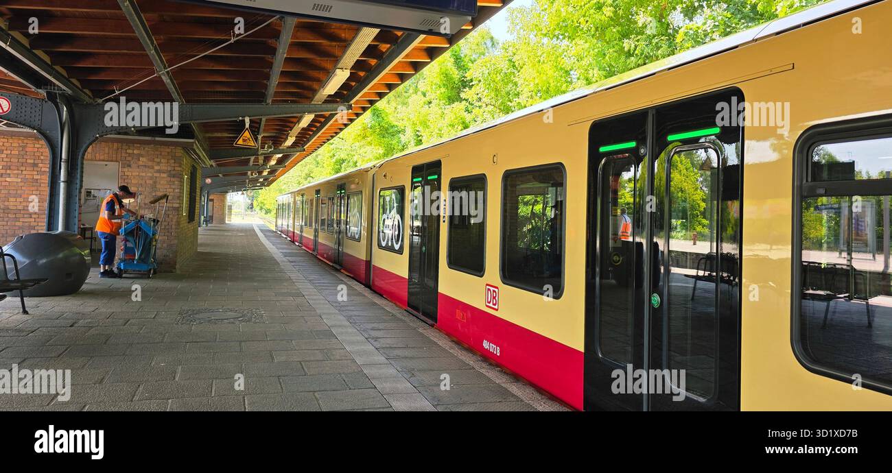 Berlin, Germany - June 13, 2025: Train is stationed at platform while worker prepares for departure in urban environment. - Smartphone Captured Stock Image