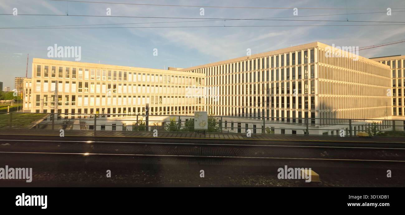 Berlin, Germany - June 13, 2025: Modern architectural structure features a glass facade and green landscaping nearby. - Smartphone Captured Stock Image