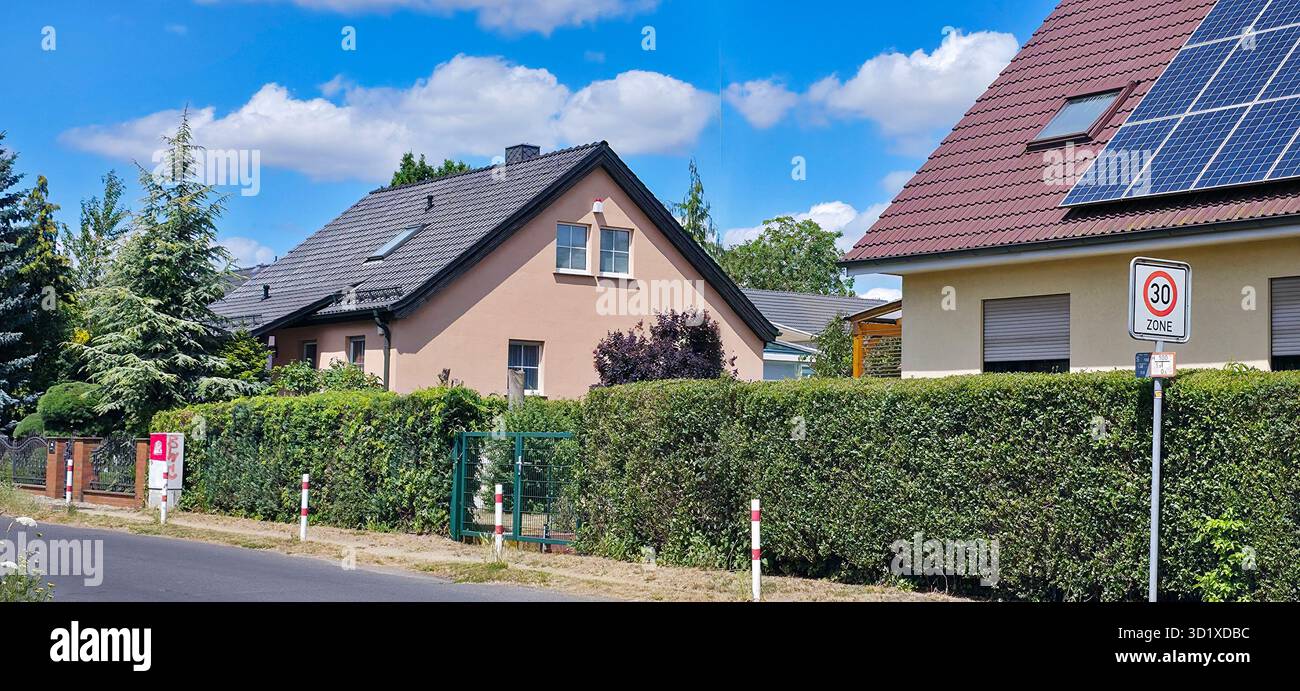 Berlin, Germany - July 04, 2025: Two residential homes featuring solar panels, surrounded by lush greenery and a clear blue sky. - Smartphone Captured Stock Image