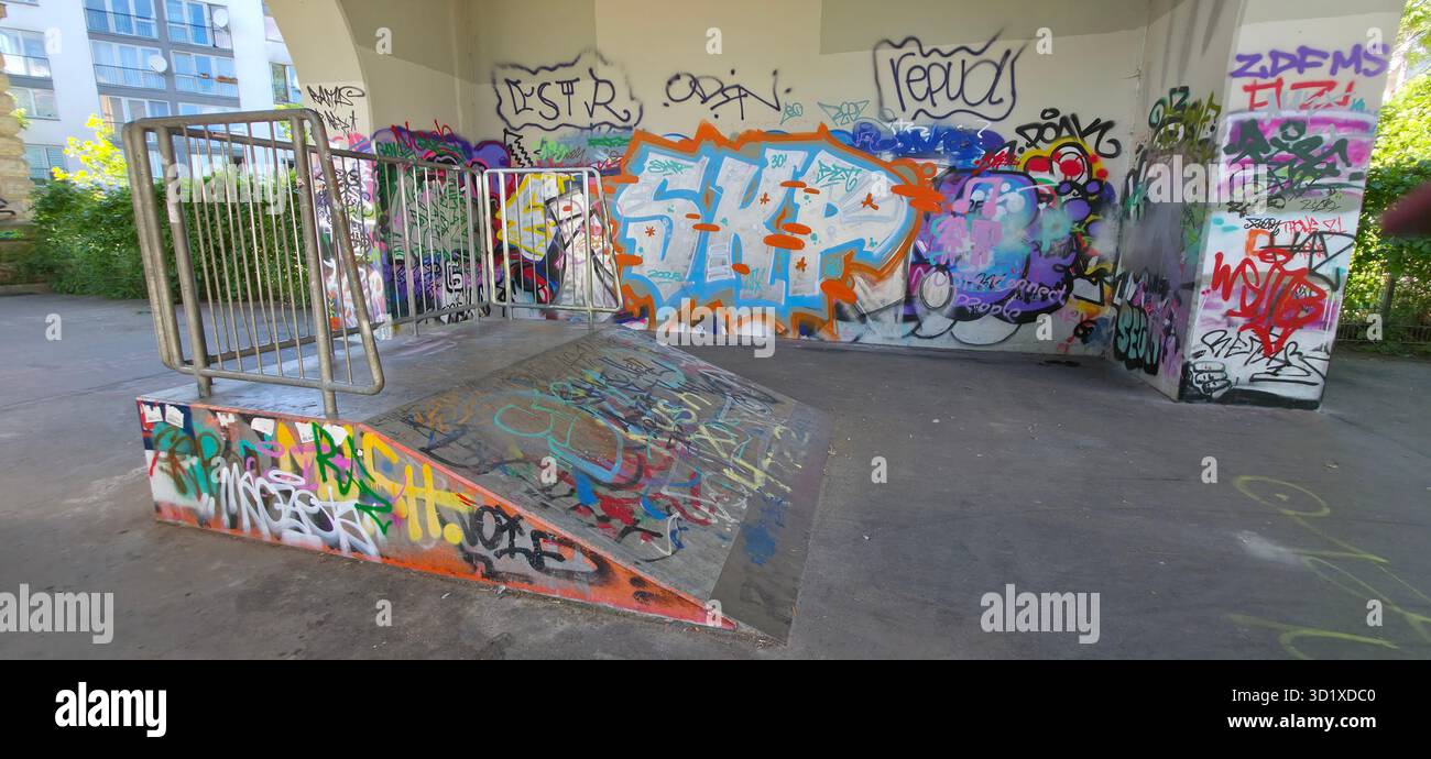 Berlin, Germany - July 04, 2025: Skate park ramp features vibrant graffiti art, showcasing urban culture and creativity in a lively environment. - Smartphone Captured Stock Image