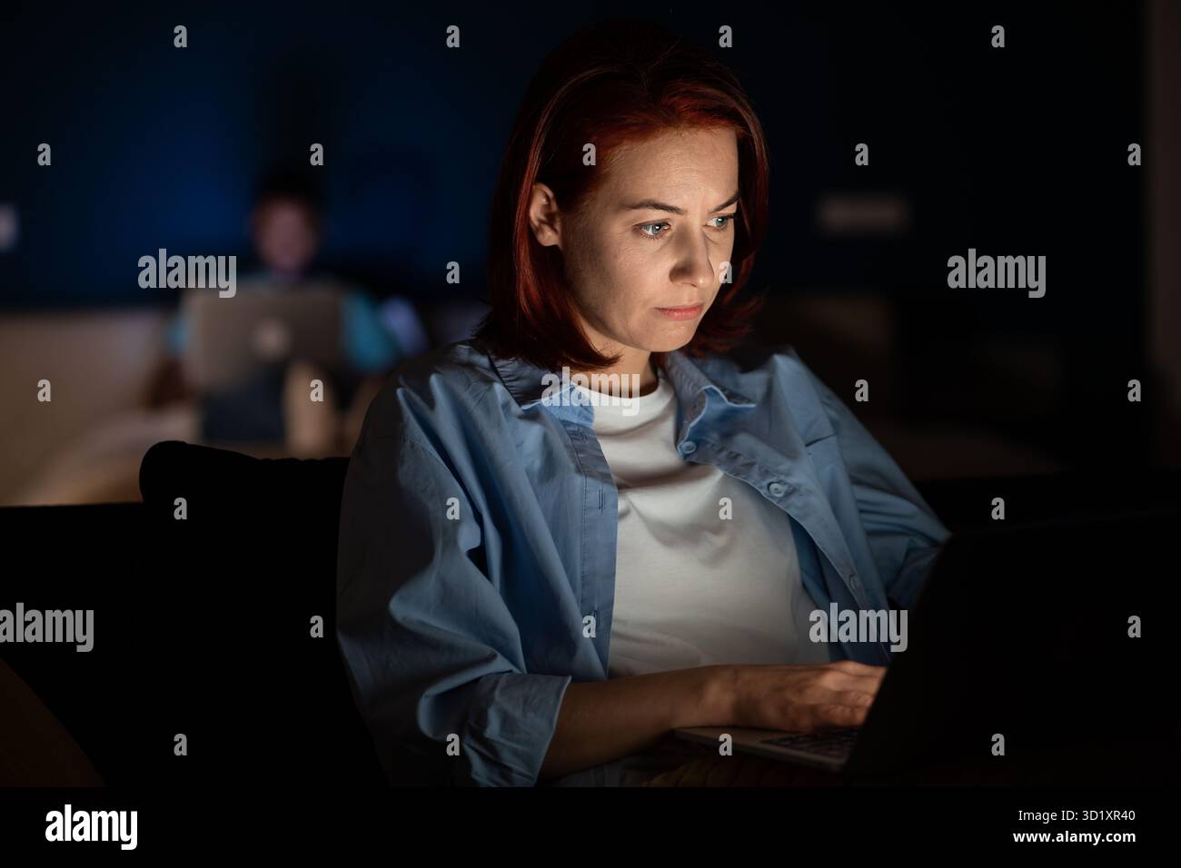 Woman uses laptop, works, studies. Overwork until late in evening, fatigue, hard study Stock Photo