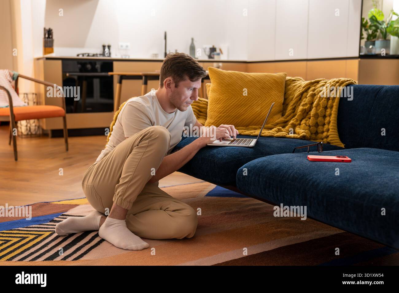 Focused IT guy sitting on floor with laptop working at home testes software websites digital product Stock Photo